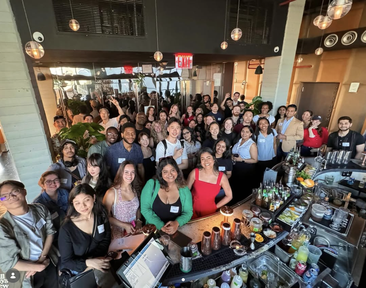 A packed room of designers smiling for a group photo by the bar